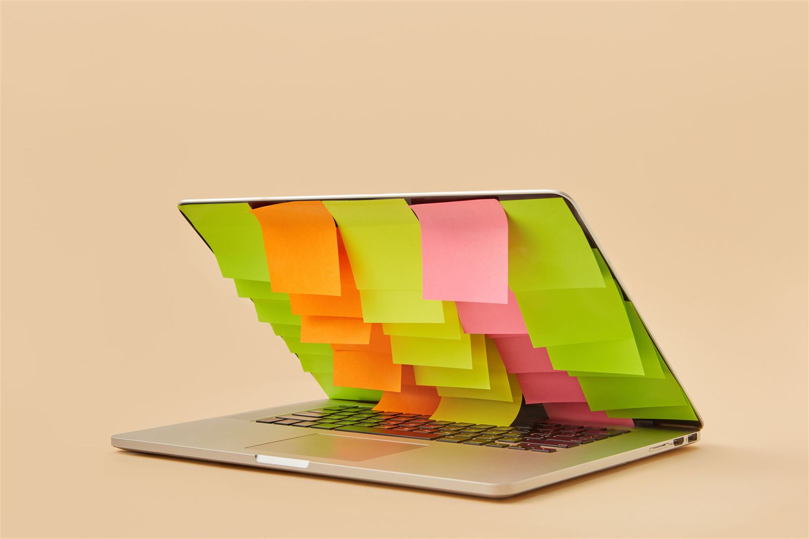 Un ordinateur portable couvert de notes autocollantes de toutes les couleurs, symbole des fiches personnages et notes d'univers éparpillées autour d'un manuscrit sur Google Docs