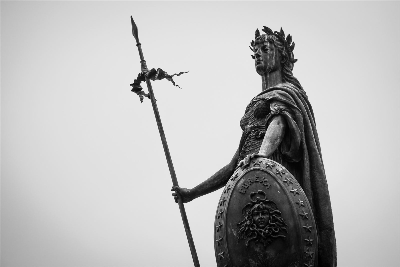 Statue de guerrière tenant une lance et un bouclier, symbole des forces qui s'affrontent dans un roman