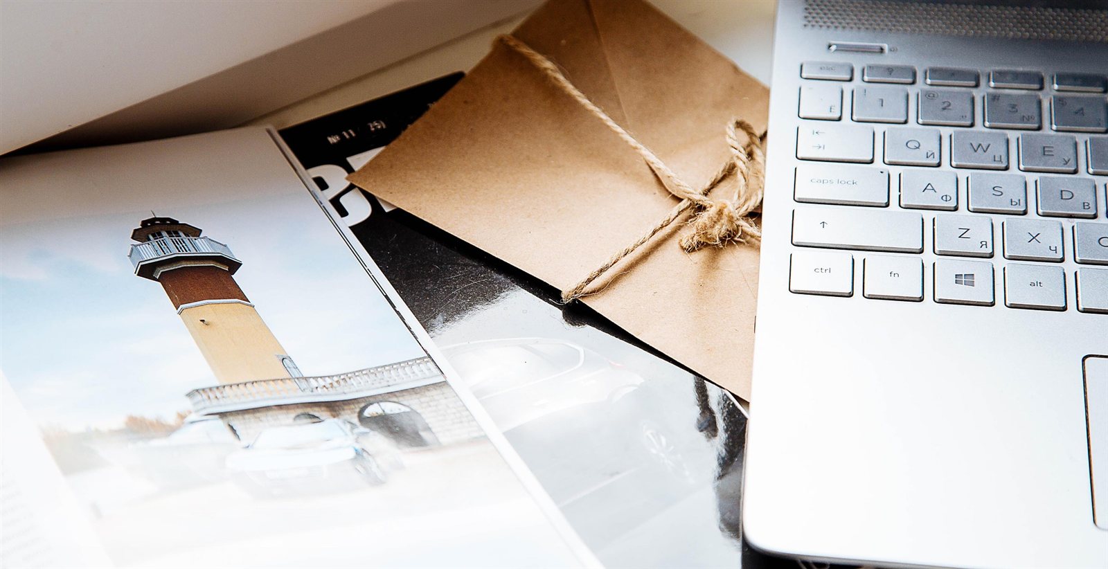Un bureau encombré de magazines et de courrier à côté d'un ordinateur portable fermé, symbole des distractions qui repoussent le moment de s'asseoir pour écrire